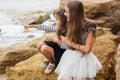 Portrait of two cute sisters sitting on the beach