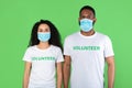 Portrait Of Two Diverse Volunteers Wearing Face Masks, Green Background