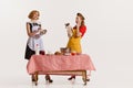 Portrait of two elegant, stylish women doing cooking together and discussing rumors isolated over white background Royalty Free Stock Photo