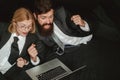 Portrait of two excited business people looking at a laptop screen. Hackers using laptops. Hackers hacking in the dark.
