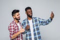 Portrait of a two excited young men taking a selfie while standing together isolated over gray background Royalty Free Stock Photo