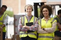 Portrait Of Two Female Workers Using Headsets In Distribution Warehouse With Digital Tablet Royalty Free Stock Photo