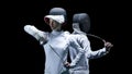 Portrait of two fencers on a black background. The concept of fencing. Duel Royalty Free Stock Photo