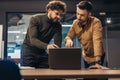 Portrait of two focused male professionals working on startup project together, discussing ideas, using laptop at office Royalty Free Stock Photo