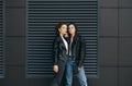 Portrait of two girlfriends in casual clothes, wearing leather jackets and jeans, standing on a black background, posing at the Royalty Free Stock Photo