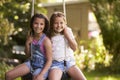 Portrait Of Two Girls Playing On Tire Swing In Garden Royalty Free Stock Photo