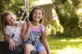 Portrait Of Two Girls Playing On Tire Swing In Garden Royalty Free Stock Photo