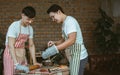 Portrait two handsome adult Asian men or friends wearing casual, aprons, holding cooking together in kitchen at home during Royalty Free Stock Photo