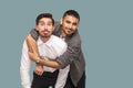 portrait of two handsome happy bearded friends standing, enjoying, hugging and looking at camera with smile and funny face and to