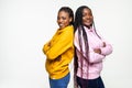 Portrait of two happy african women smiling while standing back to back over whitebackground