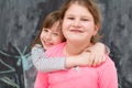 Little girls hugging in front of chalkboard Royalty Free Stock Photo
