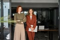 Portrait of two happy elegant business women standing at work in modern office. Royalty Free Stock Photo