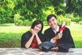 A man and woman couple dressed in black graduation gown or graduates with congratulations with graduation hats is sitting