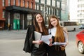 Portrait of two happy office workers standing on the street with a laptop and business papers in their hands and posing at the Royalty Free Stock Photo