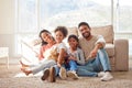 Portrait of two happy parents bonding with their daughters in the lounge, sitting on the floor. Smiling young family Royalty Free Stock Photo