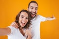 Portrait of two happy people man and woman smiling while taking selfie photo, isolated over yellow background Royalty Free Stock Photo