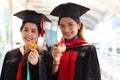 Portrait of two happy smiling graduated students holding  gold medal award, young beautiful Asian women looking at camera so proud Royalty Free Stock Photo