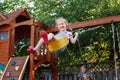 Caucasian girl toddler on swing on backyard playground outside