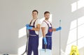 Portrait of two happy, smiling male janitors in uniforms with cleaning equipment Royalty Free Stock Photo