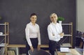 Portrait of two happy business people standing in office, smiling and looking at camera Royalty Free Stock Photo