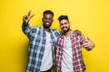 Portrait of a two happy young men in sunglasses showing peace gesture over yellow background Royalty Free Stock Photo