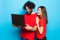 Portrait of a two happy young men and woman holding laptop computer isolated over blue background Royalty Free Stock Photo