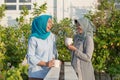 Portrait of two hijab women drinking tea in front of the house and talking