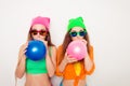 Portrait of two hipster girls in glasses blowing balloons Royalty Free Stock Photo