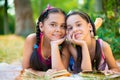 Portrait of two hispanic sisters reading in the park