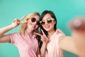 Portrait of two joyful women vin sunglasses isolated on blue