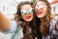 Gorgeous brunette girlfriends with hairstyle, mirrored sunglasses and red lips making selfie with duck face. Royalty Free Stock Photo