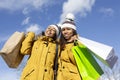 Portrait of two latin women with their shopping bags outdoors. Blue sky