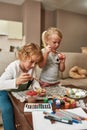 Portrait of two little children, brother and sister looking focused while painting colorful Easter eggs, sitting on a Royalty Free Stock Photo