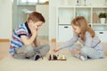 Portrait of two little children concentrated playing chess