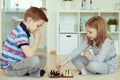 Portrait of two little children concentrated playing chess