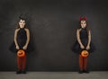 Portrait of two little girls in Halloween images standing on both sides on black background.