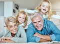 Portrait of two little girls spending time with their grandparents on the lounge floor at home . Mature caucasian couple Royalty Free Stock Photo