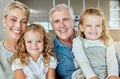 Portrait of two little girls spending time with their grandparents on a sofa at home . Mature caucasian couple Royalty Free Stock Photo