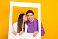 Portrait of two lovely persons picture paper frame kiss cheek isolated on yellow color background