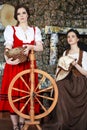 Portrait of Two Lovely Smiling Caucasian Ladies Posing With Spinning Wheel And Fancywork Hoop in Retro Dress In Rural Environment