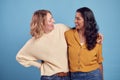 Portrait Of Two Mature Female Friends Laughing At Camera Against Blue Background Royalty Free Stock Photo
