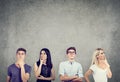 Portrait of two young men and two women thinking hard looking up standing near a concrete wall. Royalty Free Stock Photo