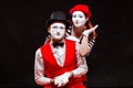 Portrait of two mime artists, isolated on black background. Woman appears from behind a man smiling. Symbol of happy Royalty Free Stock Photo