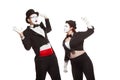 Portrait of two mime artists performing, isolated on white background. Woman raised her fist at the man. Symbol of fight