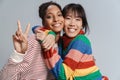 Portrait of two multinational women hugging and gesturing peace sign Royalty Free Stock Photo