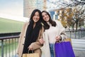 Portrait of two multiracial women carryng shopping bags and smiling looking at camera. A couple of happy females