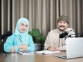 Portrait of two muslim radio hosts talking and smiling while sitting near microphones in broadcasting studio Royalty Free Stock Photo