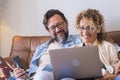 Portrait of two people man and woman enjoy technolofy connection toether with laptop and phone smiling and watching the computer