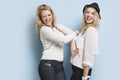 Portrait of two playful young women sticking out tongues against light blue background Royalty Free Stock Photo