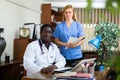 Portrait of two positive doctors of different nationalities, who are in the resident's office of the clinic